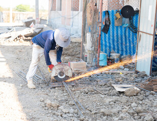 Construction worker using a circular saw to cut steel rebar with sparks flying.