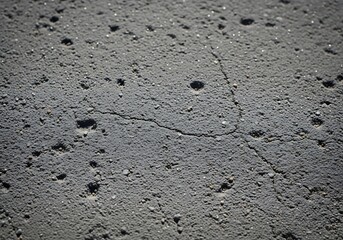 Rough gray asphalt surface with cracks and holes