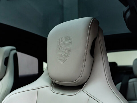 Porsche Taycan interior headrest crest detail, Electric luxury sedan white leather seats with logo stamp