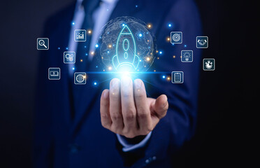 Obraz premium Businessman holding glowing startup rocket icon with global network and business strategy symbols. Innovation, digital transformation, growth strategy and global expansion concept.