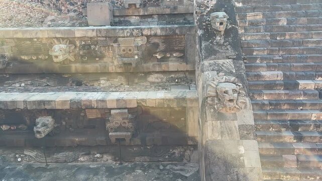 Close-up of carved stone serpent heads and ancient reliefs on Teotihuacan&rsquo;s Temple of Quetzalcoatl, with sun flare and weathered textures for history documentary b-roll.