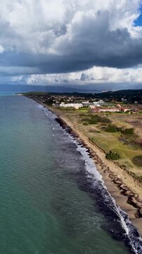 Vertical Aerial View of Acharavi Beach North Corfu Greece with Dark Stormy Clouds, Rolling Waves, Seaweed and Coastal Resort Village