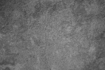 
​Gritty dark gray concrete wall texture with mottled stone surface.