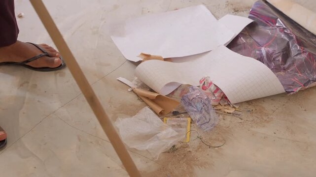 Wideangle messy floor house chores with scattered wrapping paper and glitter, flipflop foot stepping near debris while pink mop sweeps spilled fragments, upbeat postcelebration clean by host moving