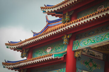 Close-up of traditional Chinese temple roof with intricate ornaments, colorful patterns and red pillars. Cultural landmark architecture with oriental design and spiritual atmosphere. © IndyTimePhoto