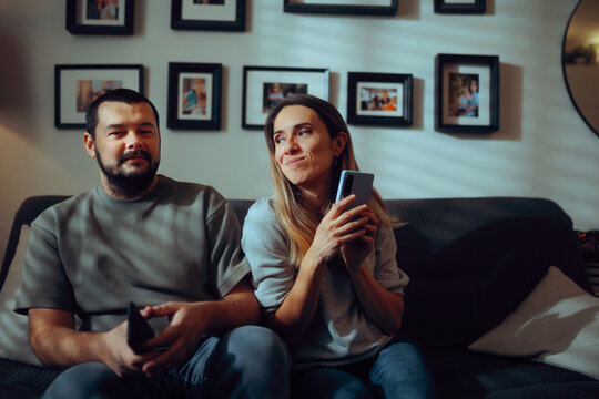 Woman Hiding her Phone while Suspicious Partner Looks Away. Secretive woman concealing her smartphone screen from her doubtful partner 