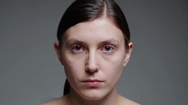 Woman With Subtle Makeup And Lighting. Studio Shot Emphasizing Skin Texture And Symmetry. Cinematic Style Portrait Showcasing Natural Expression And Delicate Makeup Against Neutral Background