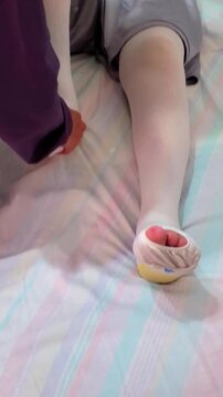 Elderly male patient lying in bed while a caregiver assists lower limb rehabilitation following fracture. Postoperative care, circulation management, and mobility recovery