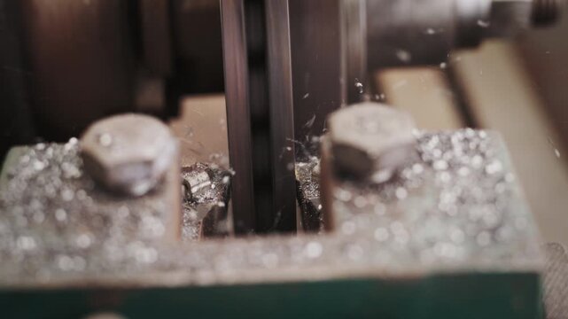 Close-up of a metal lathe cutting steel, showing flying shavings and industrial manufacturing process