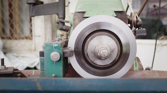 Close-up of a green antique shaper machine carving steel, producing smoke and metallic curls in a rustic workshop.