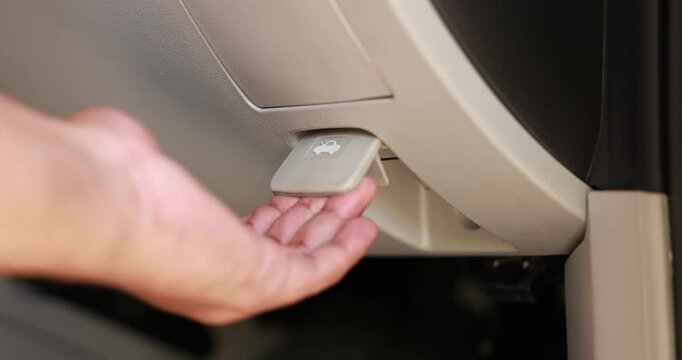 Close up of a male hand pulling the hood release lever inside a car to open the engine compartment. Driver checking vehicle before a road trip or doing auto maintenance. High quality 4K video.