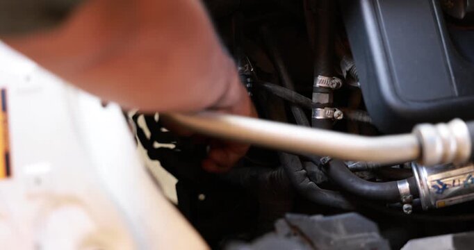 Close up male hand pulling the engine oil dipstick to check lubricant level inside a car engine bay. Driver doing routine auto maintenance and vehicle safety check before road trip. 4K video.