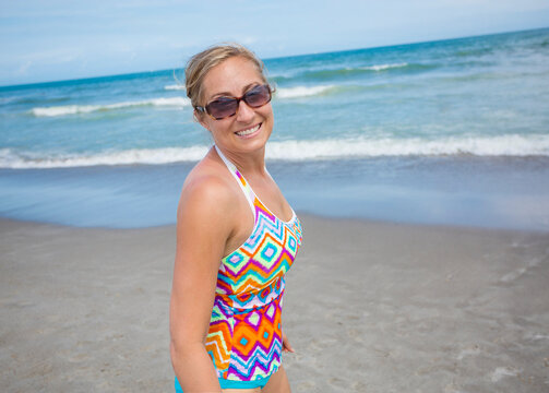 Beautiful middle-aged woman playing on a beautiful beach. Candid beach vacation lifestyle photo