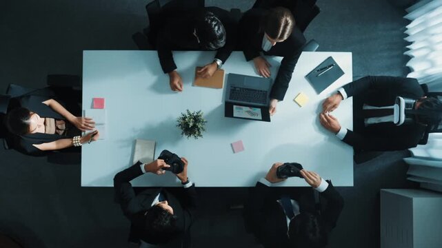 Top view of manager give vr head set to businesspeople while businesswoman prepare data analysis or financial analytic graph in laptop at meeting. Team preparing to enter meta verse. Directorate.