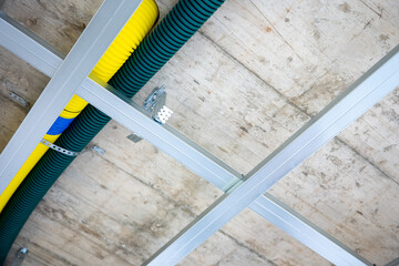 Drywall ceiling frame with ventilation pipes in new house construction. Metal structure prepared for gypsum board installation with heat recovery system ducts visible.