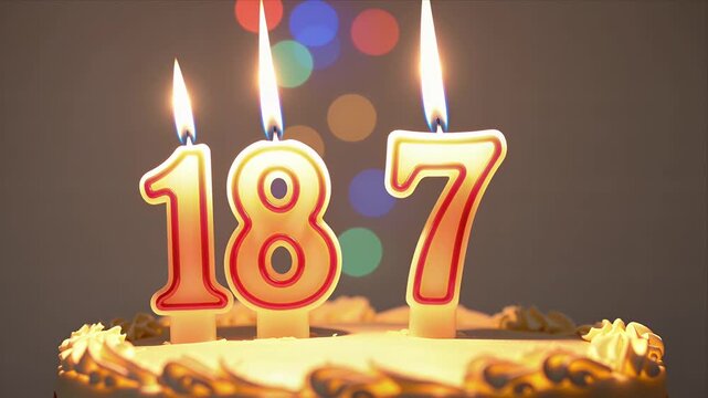 Close up of Birthday Cake with Lit Candles Shaped as 187, Warm Glowing Lights in Background for Celebration