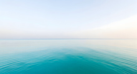Obraz premium Tranquil turquoise ocean water surface with gentle ripples under a clear pale blue sky creating a serene and peaceful natural horizon landscape