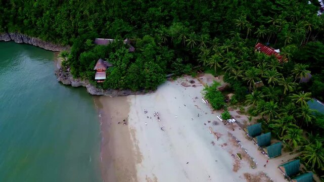 Aerial drone panning right from a moored outrigger boat in Sugar Beach to reveal the green forested mountains surrounding the shoreline in Sipalay, Negros Occidental, Philippines
