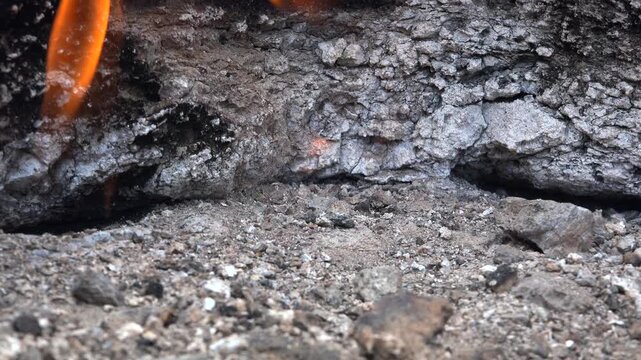 Natural methane gas fire burns between rocks on barren ground across a rugged rocky landscape. Eternal flames rise from stone gaps as subsurface fuel ignites within raw desolate terrain.