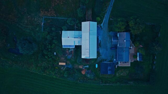 Overhead autumn farm aerial with barn, boat, greenhouse, and cultivated beds, slow left panning shot.