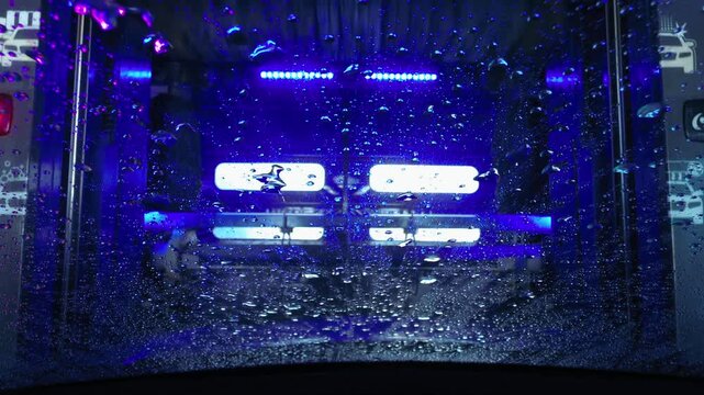 A view from inside a vehicle during an automatic car wash at a service center.