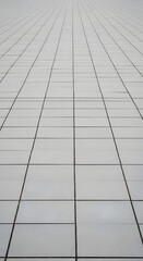 Fototapeta premium Expansive grid of light gray square tiles stretching into the distance creating a modern minimalist architectural background pattern