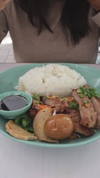 Using chopsticks to eat authentic local Vietnamese dish, thit nuong or grilled marinated pork, braised egg ( thit trung) paired with rice and goi tom or cabbage salad