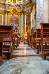 Naklejka premium Wooden chairs line the floor in a church with ornate decorations and light coming through