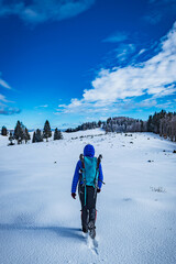 A young woman walking in the snow with a backpack
