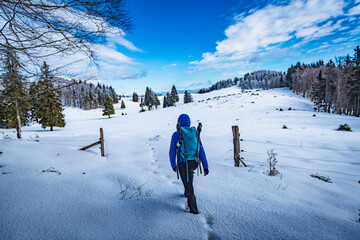 A young woman walking in the snow with a backpack