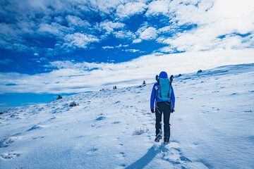 A young woman walking in the snow with a backpack