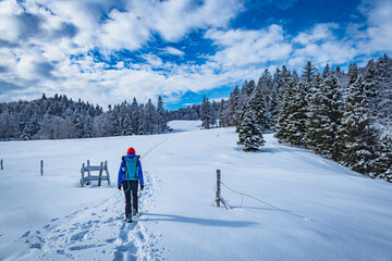 A young woman walking in the snow with a backpack