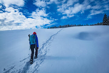 A young woman walking in the snow with a backpack