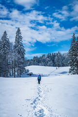 A young woman walking in the snow with a backpack