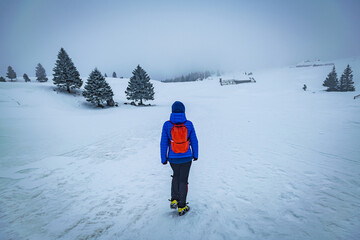A young woman walking in the snow with a backpack