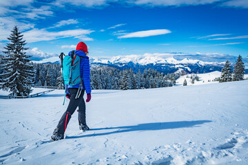 A young woman walking in the snow with a backpack