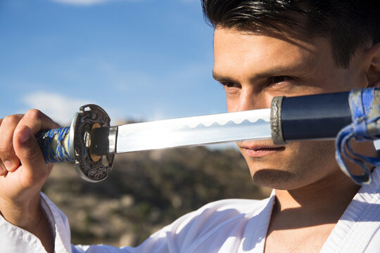 Man with defiant eyes drawing his katana sword