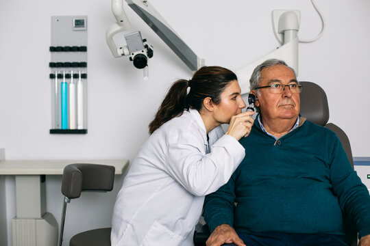 ENT physician examining ear of a senior man with an otoscope