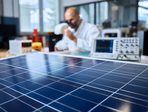 Solar panel and technician with microscope in background