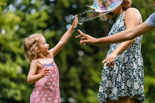 Girl exploding bubble while playing with family at park