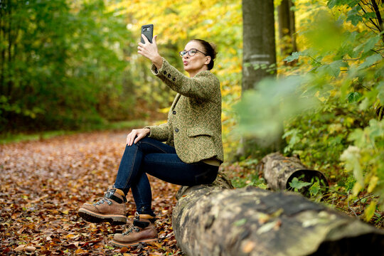 Mature woman taking a selfie in a autumn forest