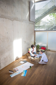 Businessman and businesswoman talking in a loft with documents on the floor