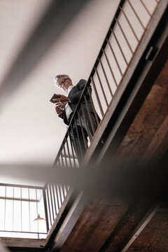 Senior businessmans standing at railing, using digital tablet