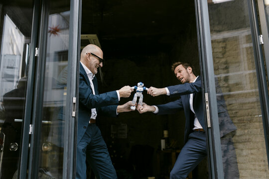 Senior and mid-adult businessman fighting for robot