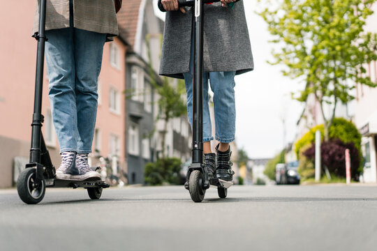 Young women riding electric scooters in the street