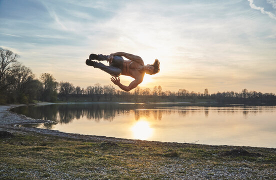 Germany, Bavaria, Feldkirchen, man doing parkour at lakeshore