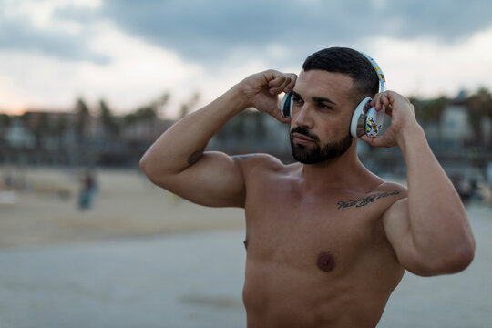 Portrait of barechested muscular man with headphones outdoors