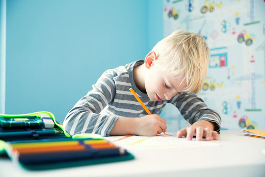 Focused boy doing homework at desk in children's room