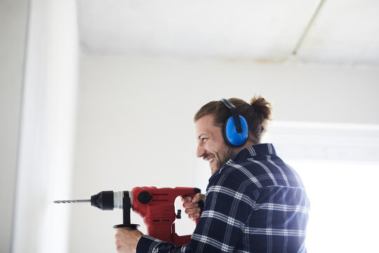 Happy worker using electric drill on a construction site