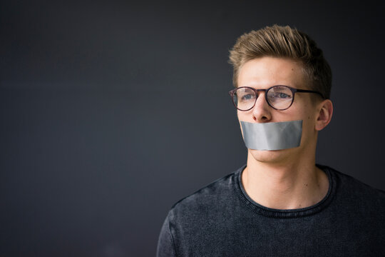 Portrait of young man with taped mouth